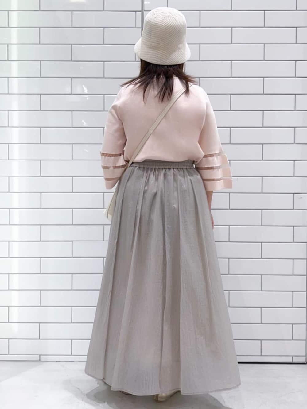 ピンク系のニット/セーター、ベージュ系のスカート、ゴールド系のパンプスを着用したレディースの春コーディネートの3枚目の写真