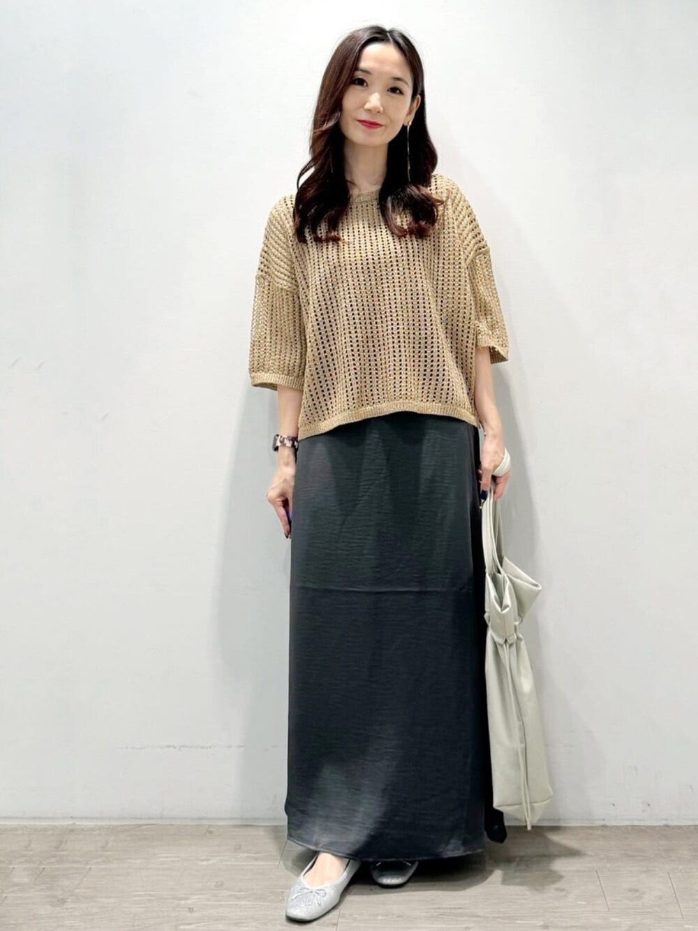 ゴールド系のニット/セーター、グレー系のトートバッグ、グレー系のスカートを着用したレディースの秋コーディネートの3枚目の写真