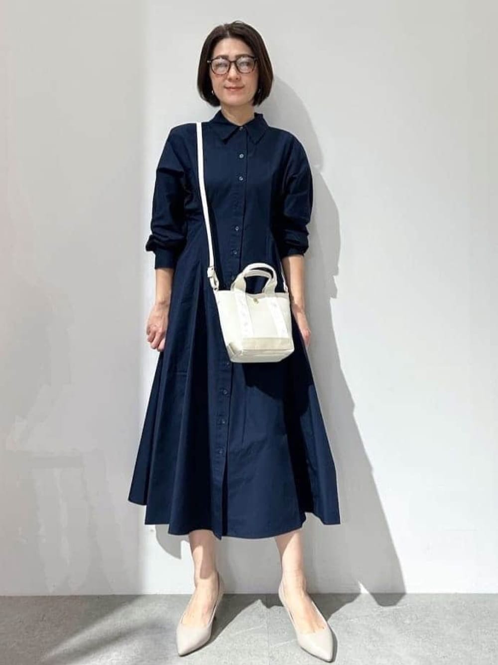 ホワイト系のベスト、ブルー系のワンピース、シルバー系のサンダルを着用したレディースの春コーディネートの3枚目の写真