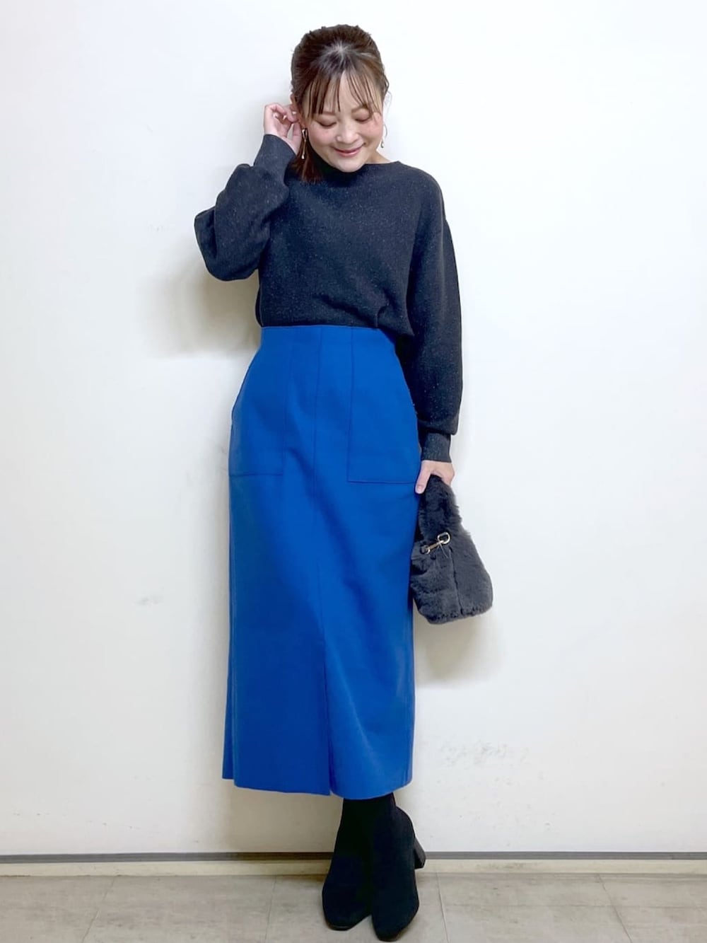 ブラック系のチェスターコート、ブルー系のスカート、ブラック系のブーツを着用したレディースの冬コーディネートの4枚目の写真