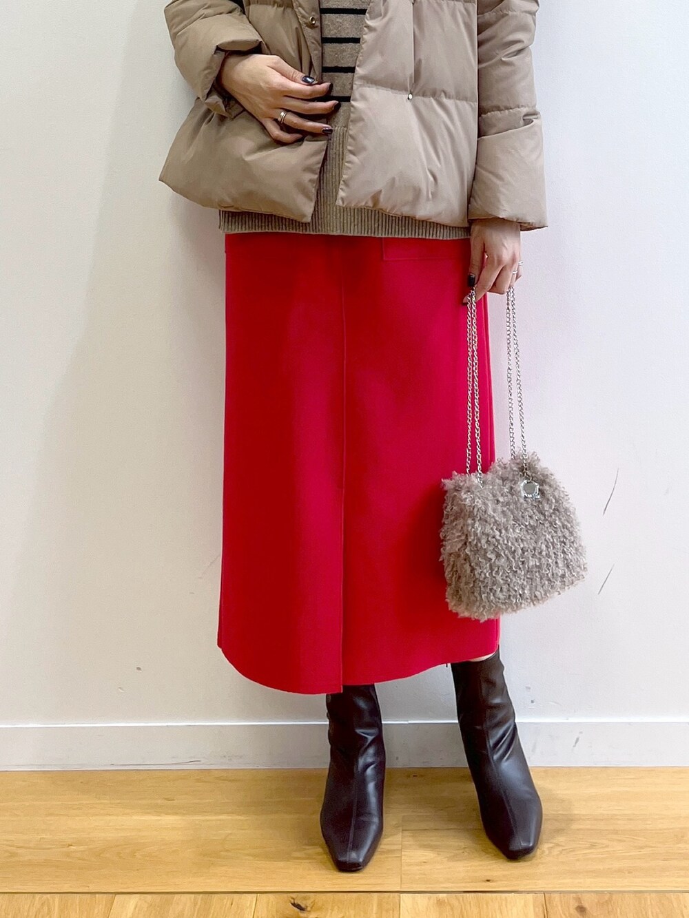 イエロー系のダウンジャケット/コート、ベージュ系のニット/セーター、レッド系のスカートを着用したレディースの秋コーディネートの7枚目の写真
