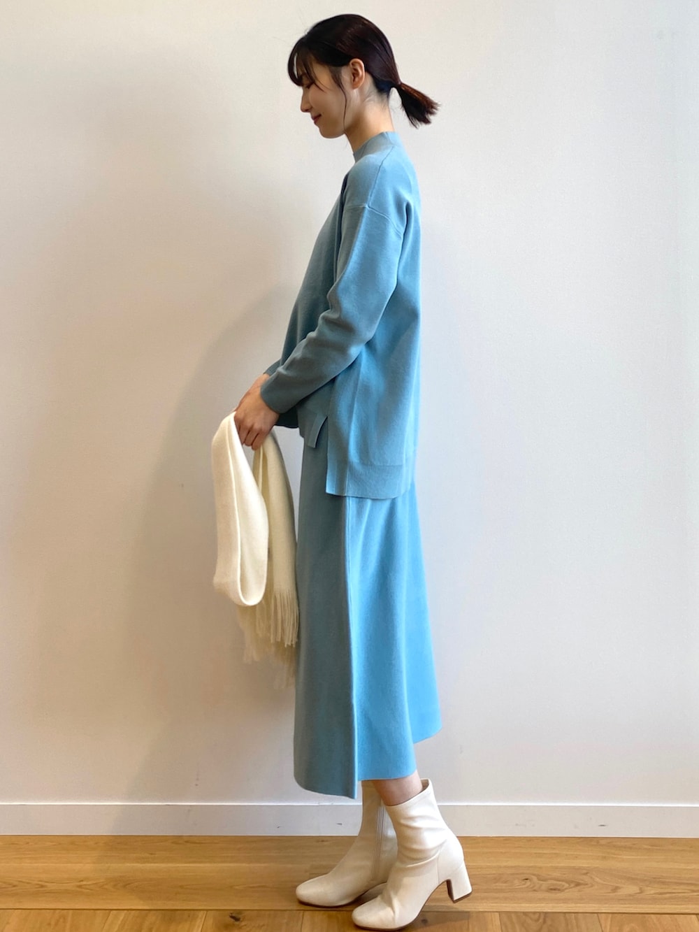 ブルー系のニット/セーター、ブルー系のスカート、ホワイト系のブーツを着用したレディースの冬コーディネートの2枚目の写真