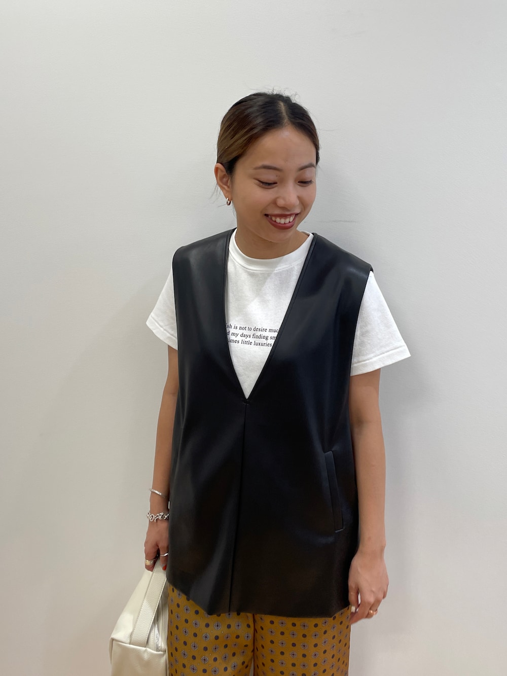 ホワイト系のTシャツ/カットソー、ブラック系のベスト、イエロー系のその他パンツを着用したレディースの夏コーディネートの3枚目の写真