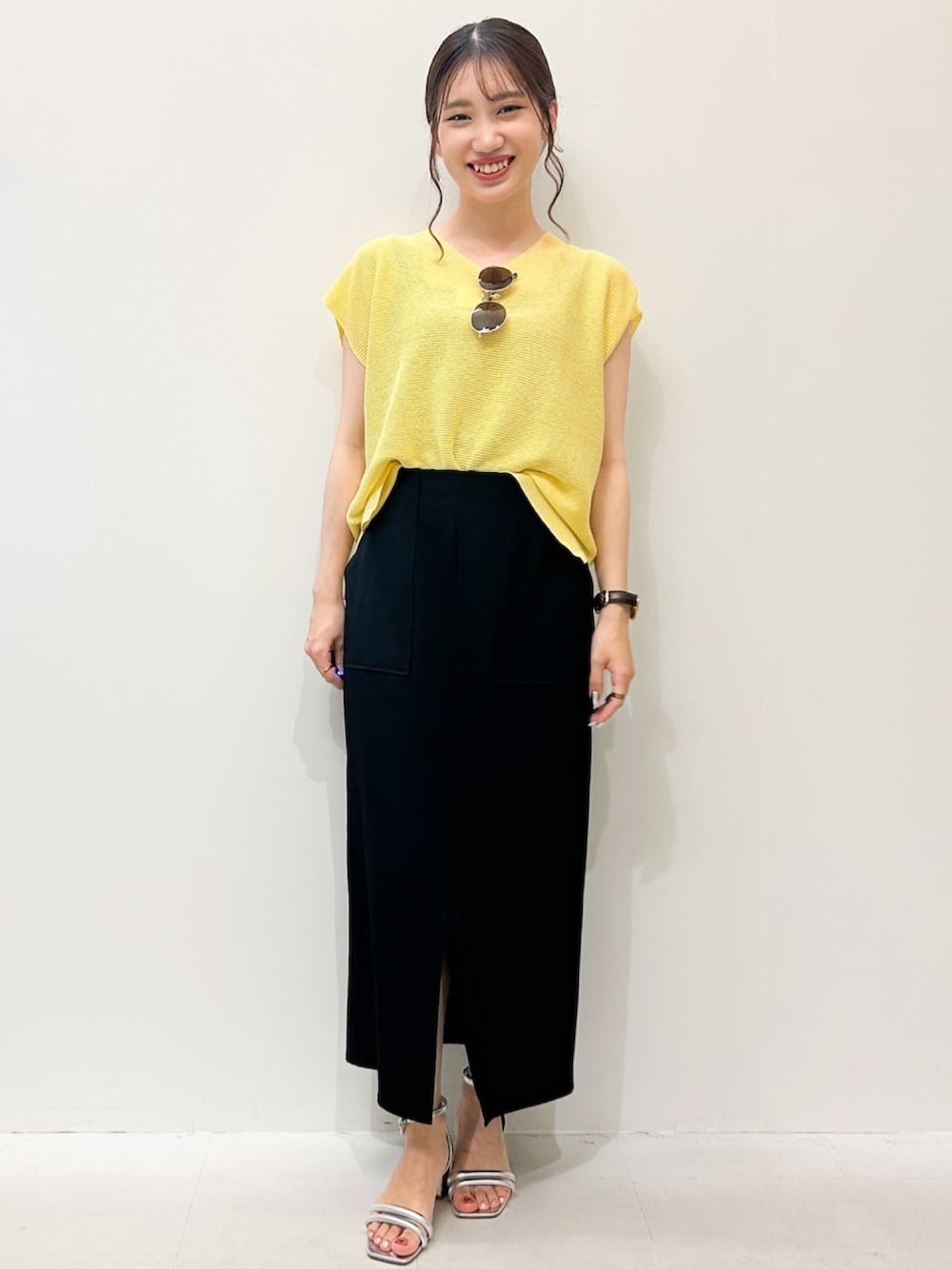 ブラック系のスカート、シルバー系のサンダル、イエロー系のニット/セーターを着用したレディースの夏コーディネートの4枚目の写真