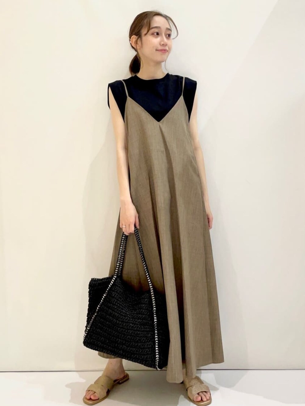 ベージュ系のワンピース、ブラック系のシャツ/ブラウス、ゴールド系のサンダルを着用したレディースの夏コーディネートの3枚目の写真