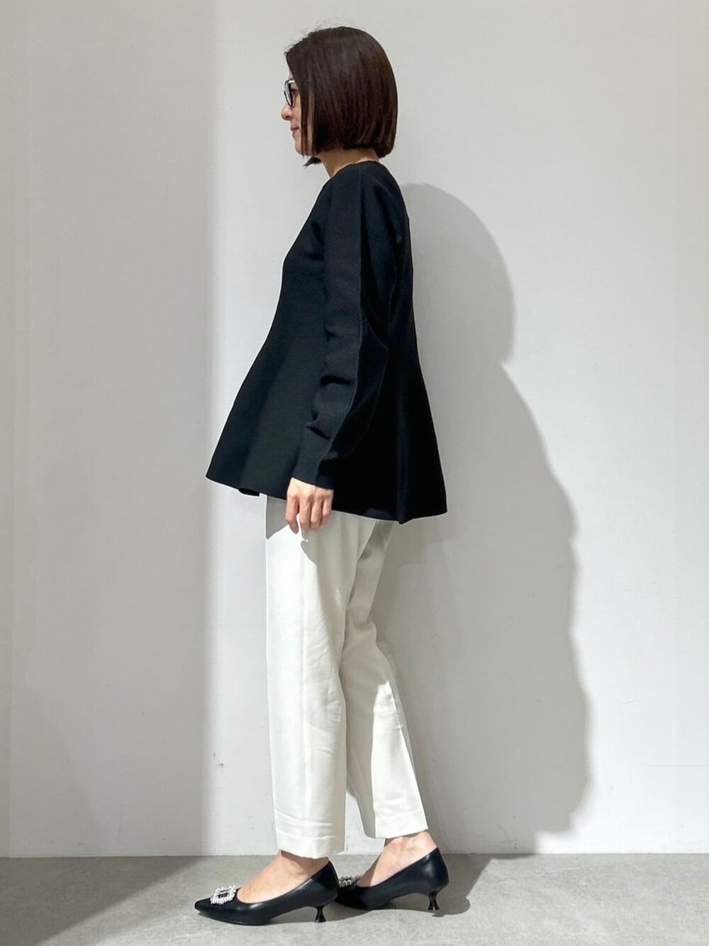 ブラック系のニット/セーター、ホワイト系のその他パンツ、ホワイト系のショルダーバッグを着用したレディースの冬コーディネートの2枚目の写真