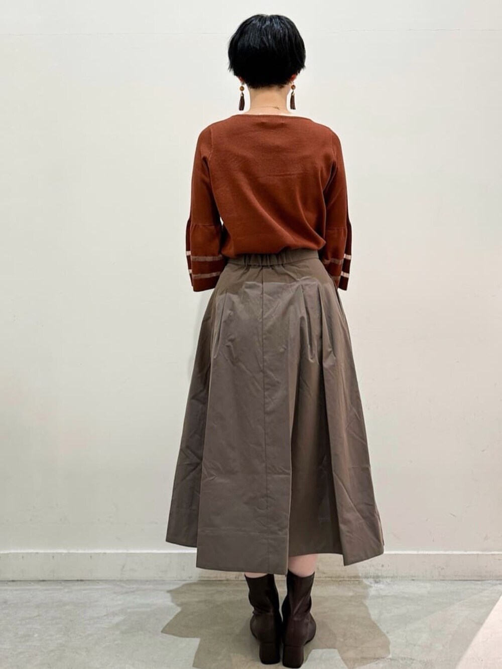 ブラウン系のスカート、グレー系のトートバッグ、ブラウン系のブーツを着用したレディースの秋コーディネートの3枚目の写真