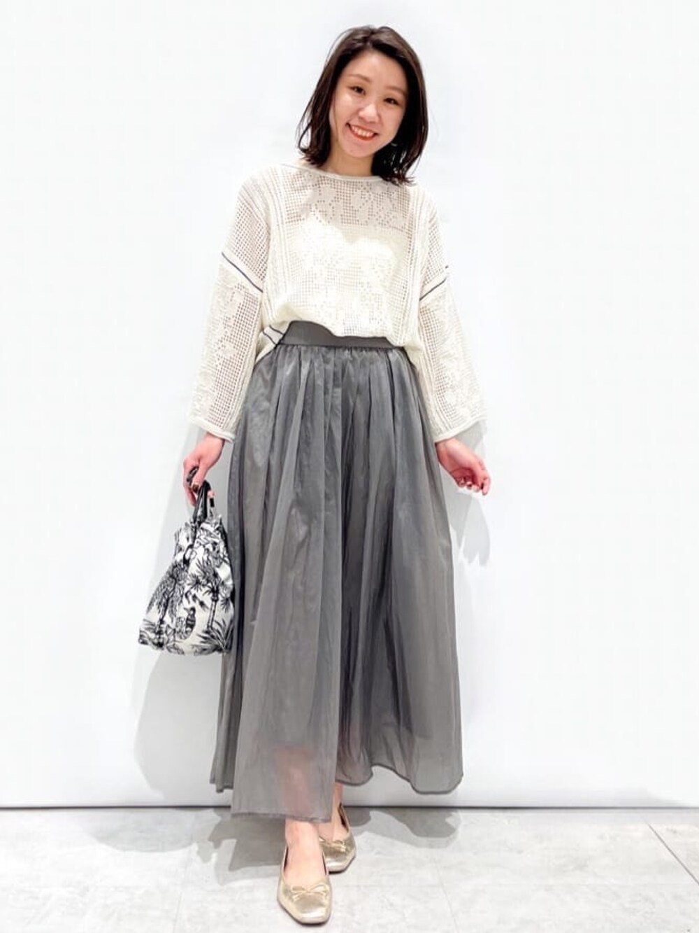 ホワイト系のニット/セーター、グレー系のスカート、ホワイト系のハンドバッグを着用したレディースの春コーディネートの4枚目の写真