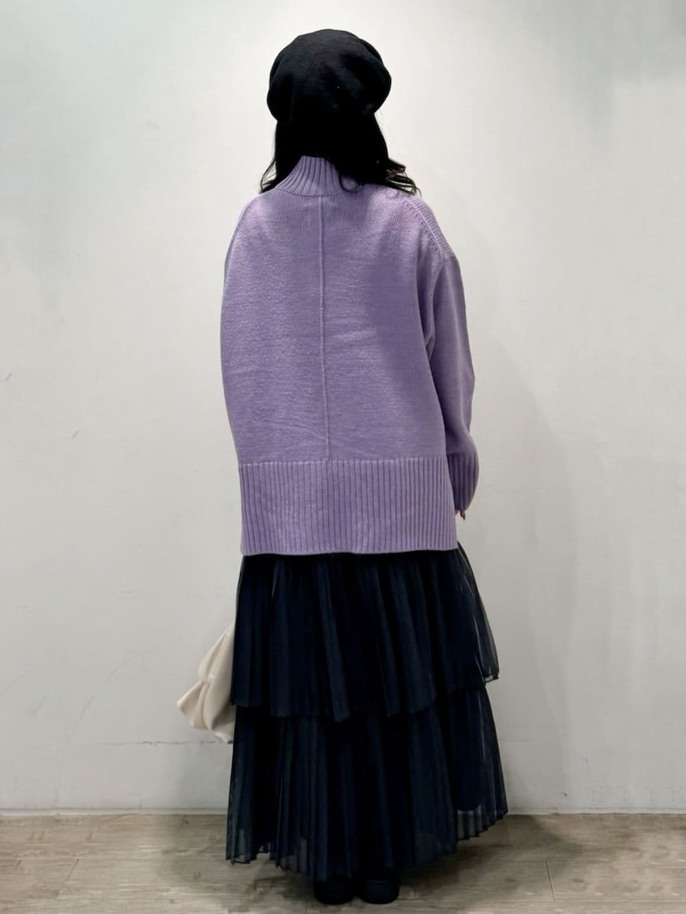 パープル系のニット/セーター、グレー系のスカート、ホワイト系のトートバッグを着用したレディースの秋コーディネートの4枚目の写真