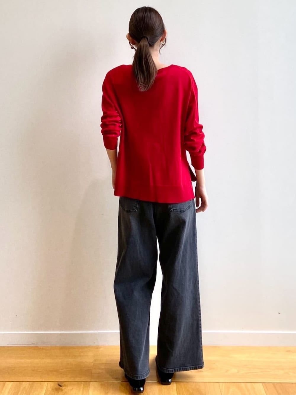 レッド系のニット/セーター、ブラック系のデニムパンツ、ブラック系のパンプスを着用したレディースの秋コーディネートの4枚目の写真