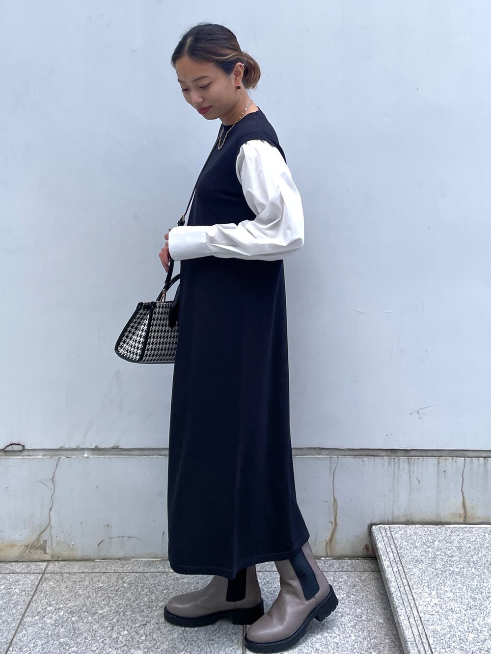 ブラック系のワンピース、ブラック系のボストンバッグ、ブラウン系のブーツを着用したレディースの秋コーディネートの2枚目の写真