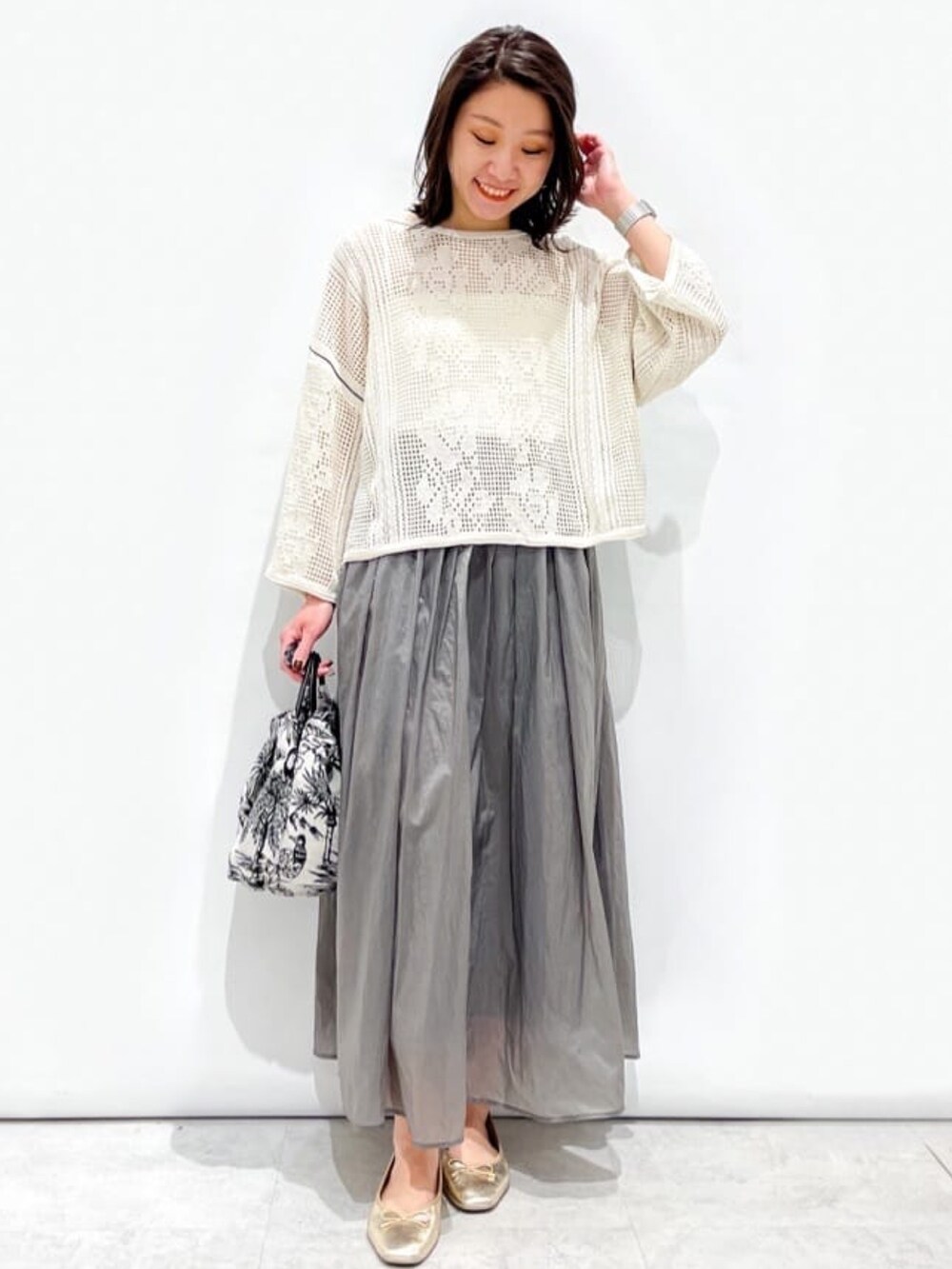 ホワイト系のニット/セーター、グレー系のスカート、ホワイト系のハンドバッグを着用したレディースの春コーディネートの7枚目の写真