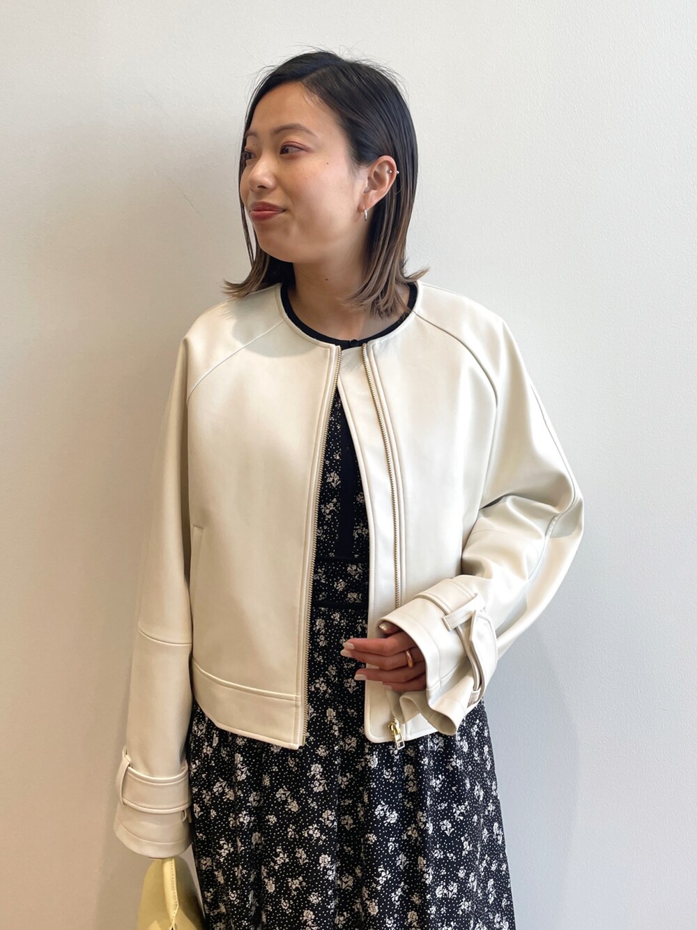 ベージュ系のノーカラージャケット、ブラック系のワンピース、イエロー系のショルダーバッグを着用したレディースの春コーディネートの4枚目の写真