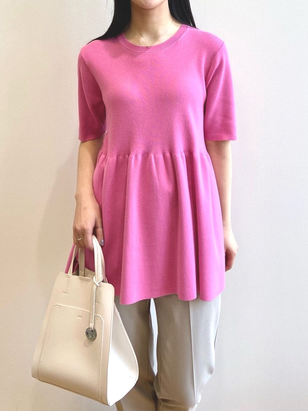 ピンク系のニット/セーター、ベージュ系のその他パンツ、ホワイト系のトートバッグを着用したレディースの夏コーディネートの4枚目の写真