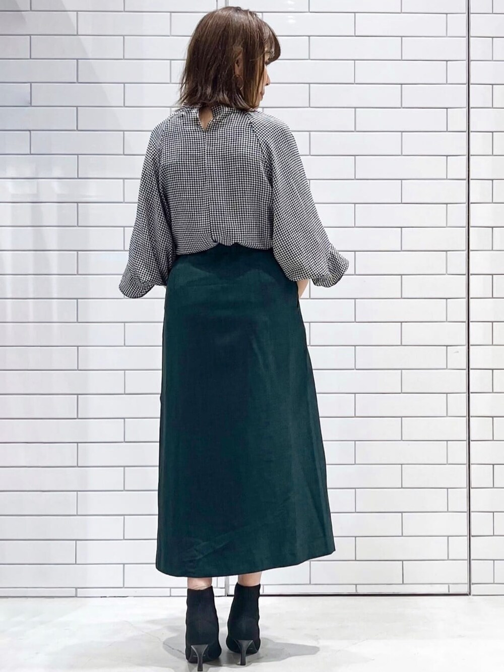 ブラック系のブーツ、ブラック系のシャツ/ブラウス、グリーン系のスカートを着用したレディースの秋コーディネートの2枚目の写真