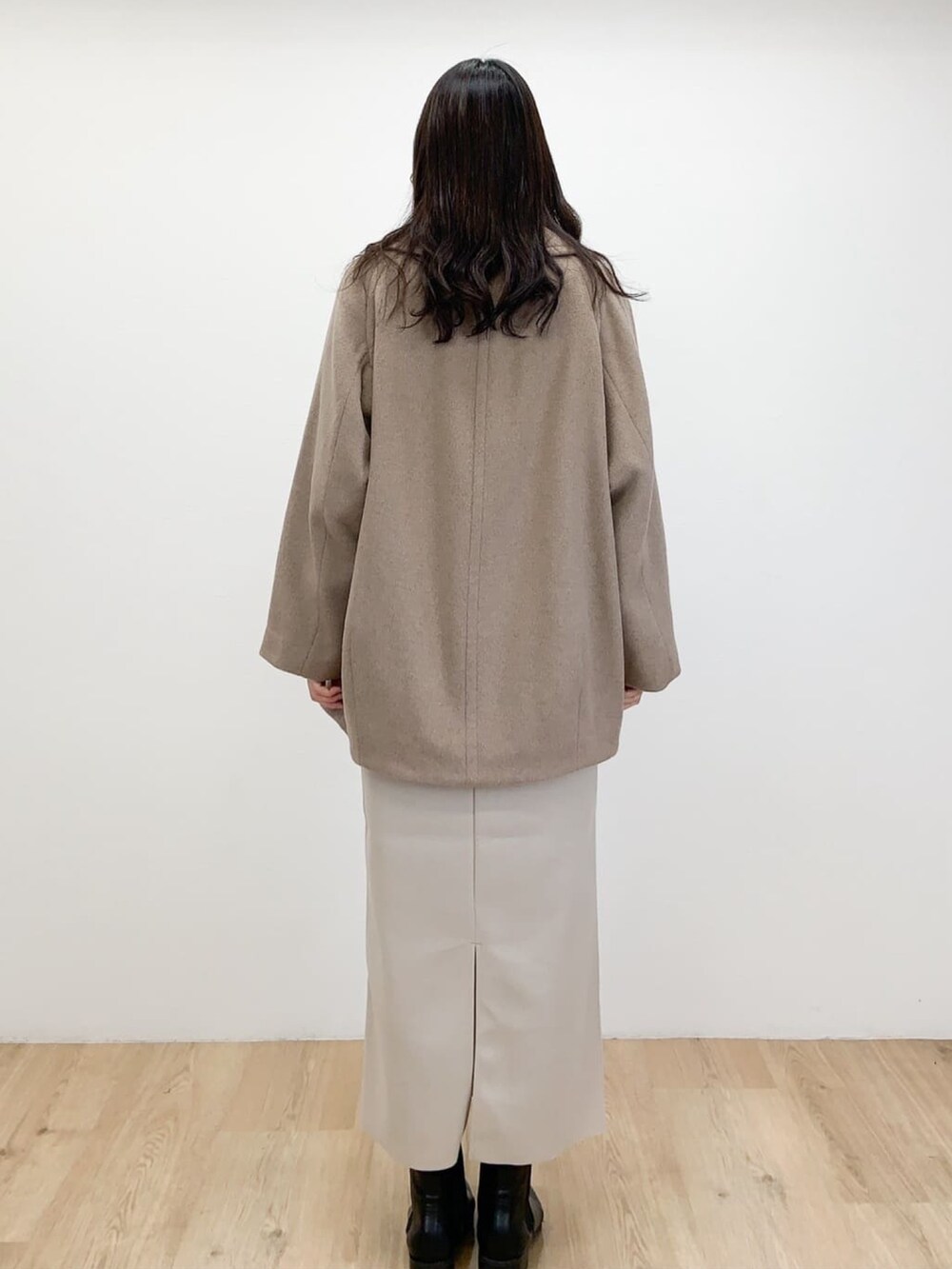 ブラウン系のピーコート、ベージュ系のスカート、ホワイト系のニット/セーターを着用したレディースの冬コーディネートの2枚目の写真