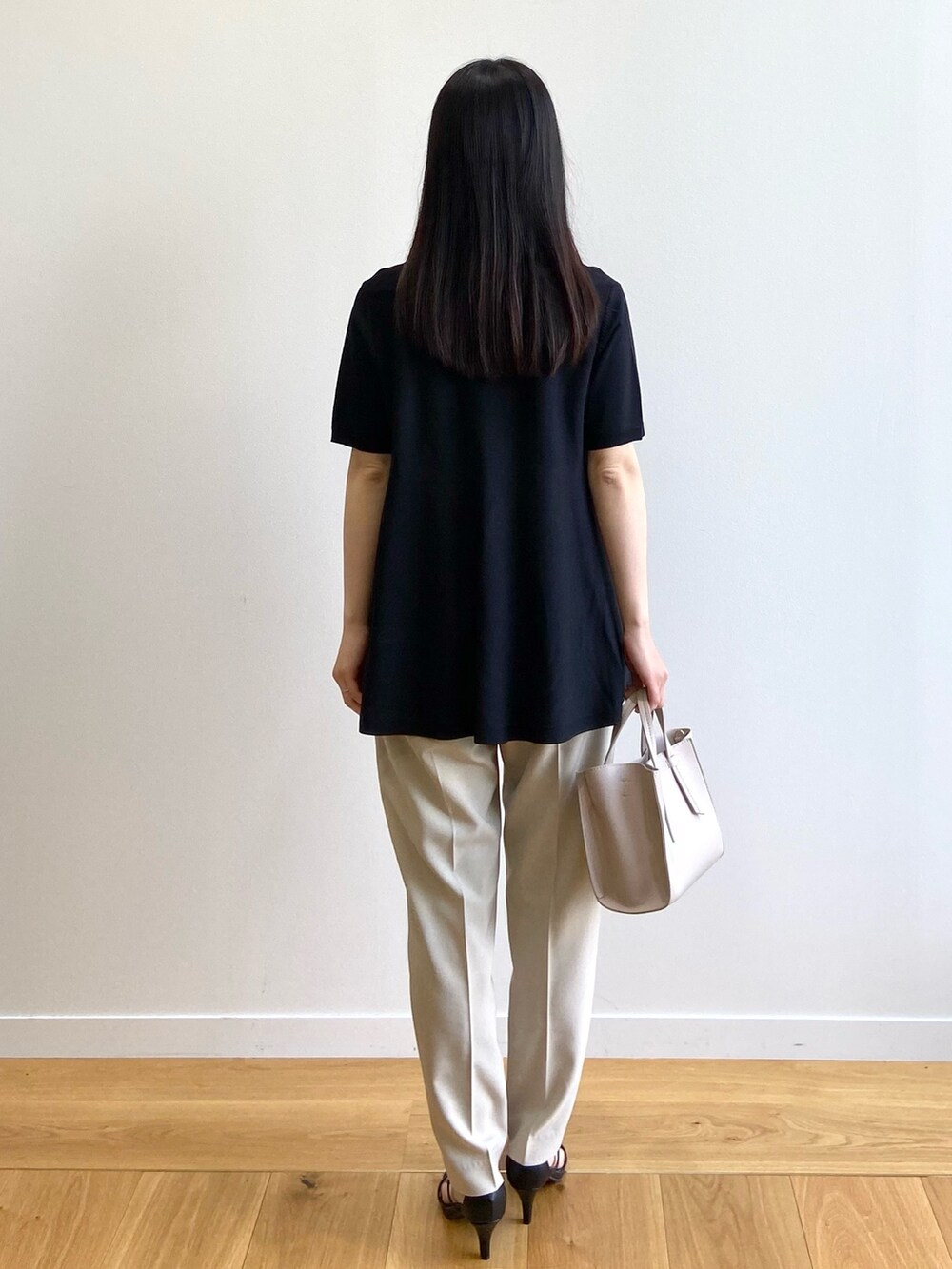 ブラック系のニット/セーター、ベージュ系のその他パンツ、ベージュ系のトートバッグを着用したレディースの春コーディネートの3枚目の写真