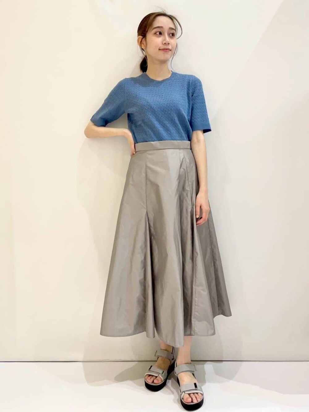 ブルー系のニット/セーター、グレー系のスカート、グレー系のサンダルを着用したレディースの夏コーディネートの2枚目の写真