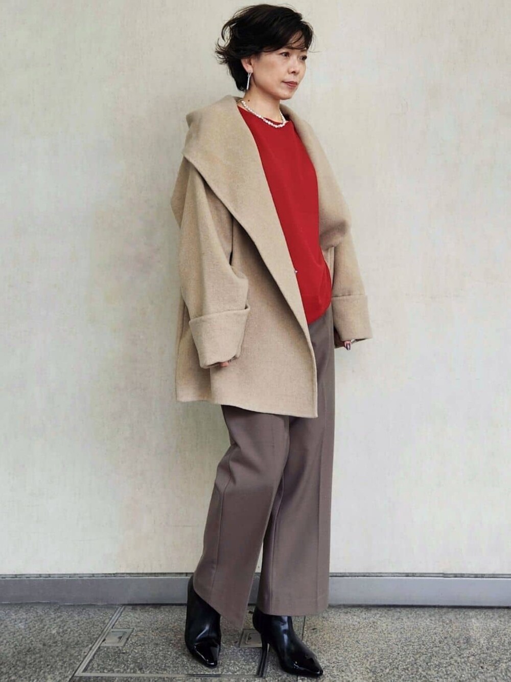 レッド系のニット/セーター、ブラウン系のその他パンツ、ベージュ系のその他アウターを着用したレディースの秋コーディネートの2枚目の写真