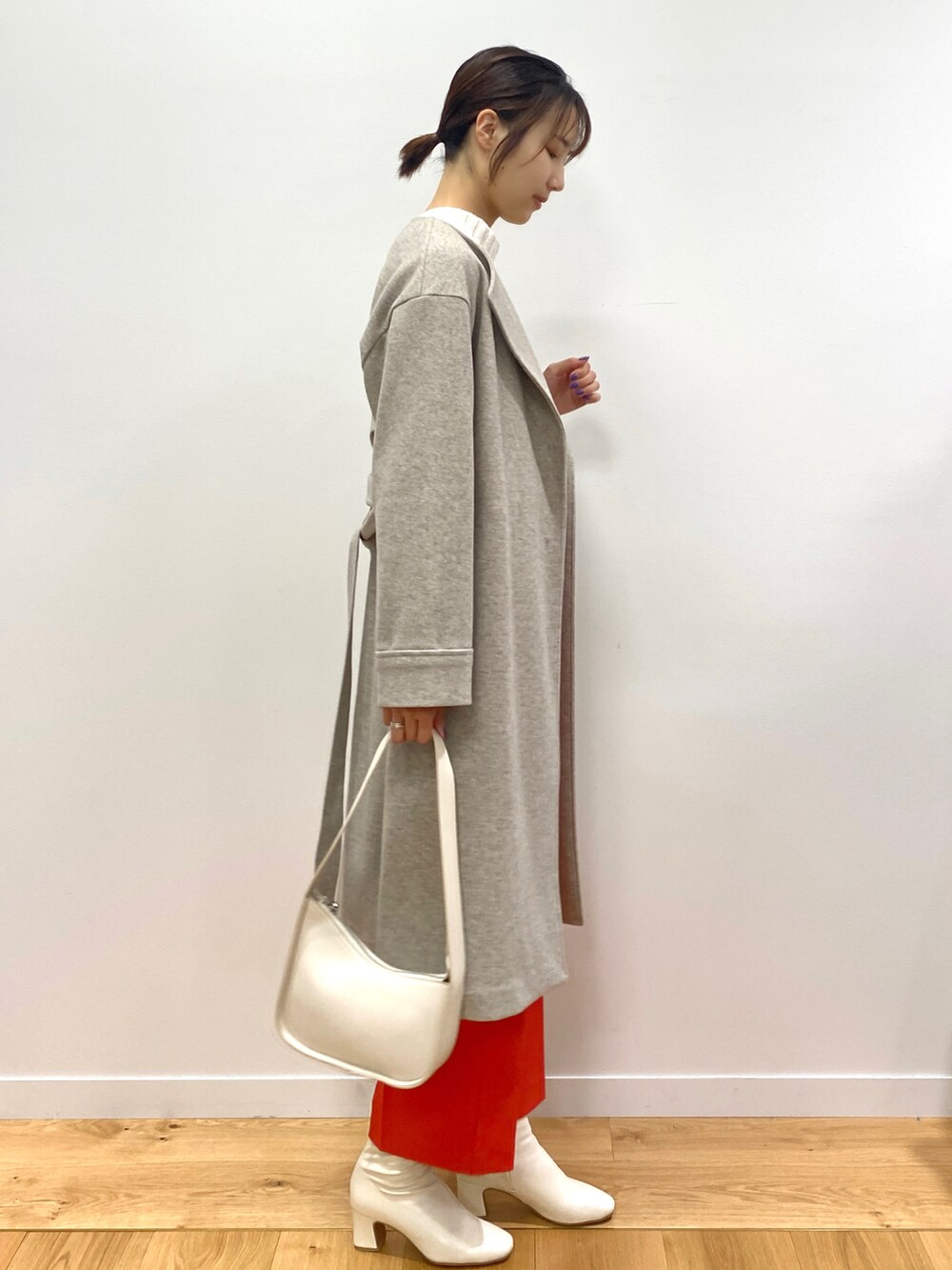 グリーン系のニット/セーター、ベージュ系のノーカラーコート、オレンジ系のその他パンツを着用したレディースの秋コーディネートの2枚目の写真