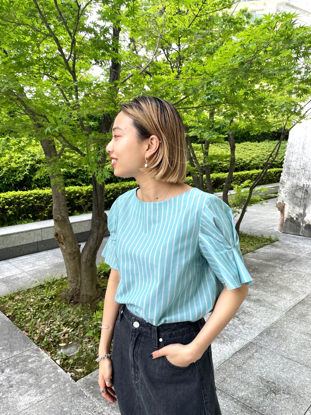 グリーン系のシャツ/ブラウス、グレー系のデニムスカート、ブラック系のサンダルを着用したレディースの夏コーディネートの2枚目の写真