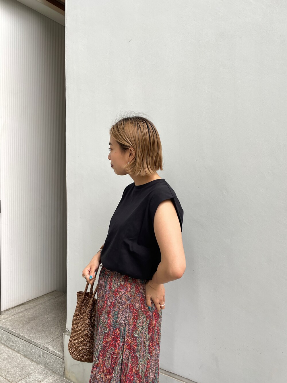 ブラック系のTシャツ/カットソー、オレンジ系のスカート、その他のトートバッグを着用したレディースの春コーディネートの3枚目の写真