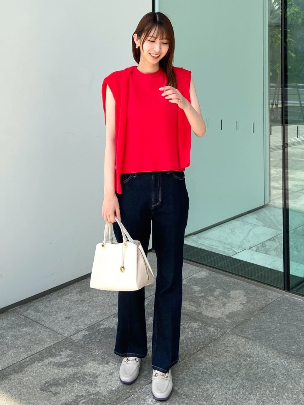 レッド系のカーディガン/ボレロ、レッド系のニット/セーター、ブルー系のデニムパンツを着用したレディースの夏コーディネートの2枚目の写真