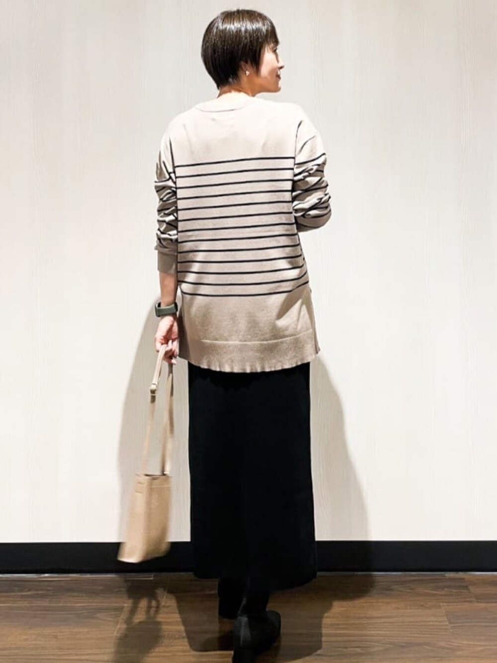 ベージュ系のニット/セーター、ベージュ系のショルダーバッグ、ブラック系のブーツを着用したレディースの秋コーディネートの3枚目の写真