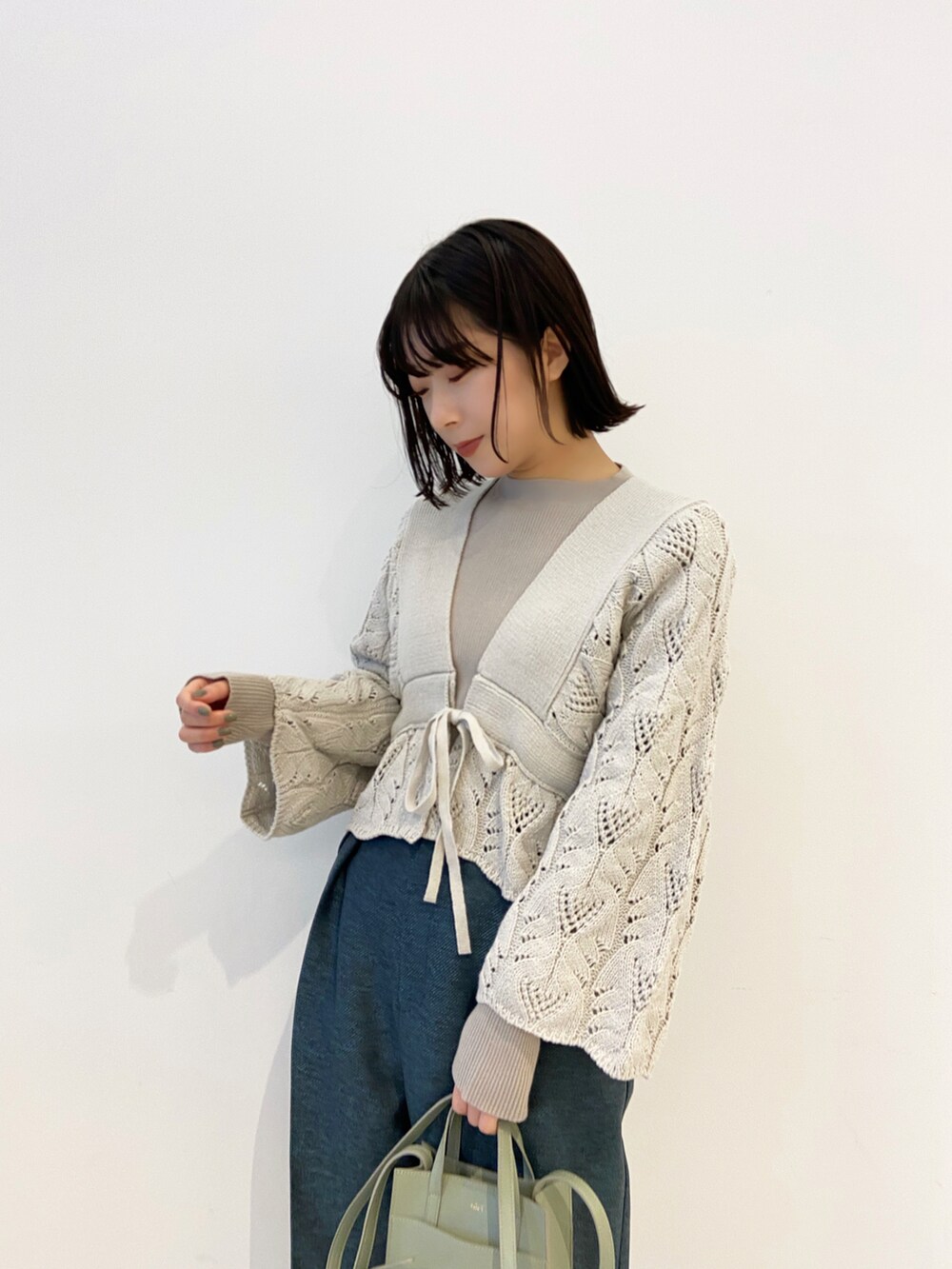 ホワイト系のカーディガン/ボレロ、ブルー系のその他パンツ、グリーン系のショルダーバッグを着用したレディースの冬コーディネートの2枚目の写真