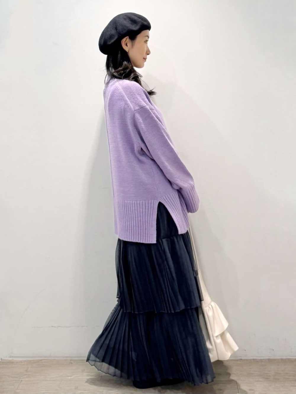 パープル系のニット/セーター、グレー系のスカート、ホワイト系のトートバッグを着用したレディースの秋コーディネートの3枚目の写真