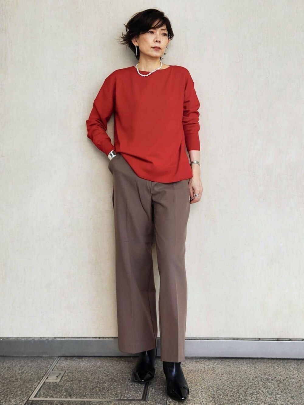 レッド系のニット/セーター、ブラウン系のその他パンツ、ベージュ系のその他アウターを着用したレディースの秋コーディネートの4枚目の写真