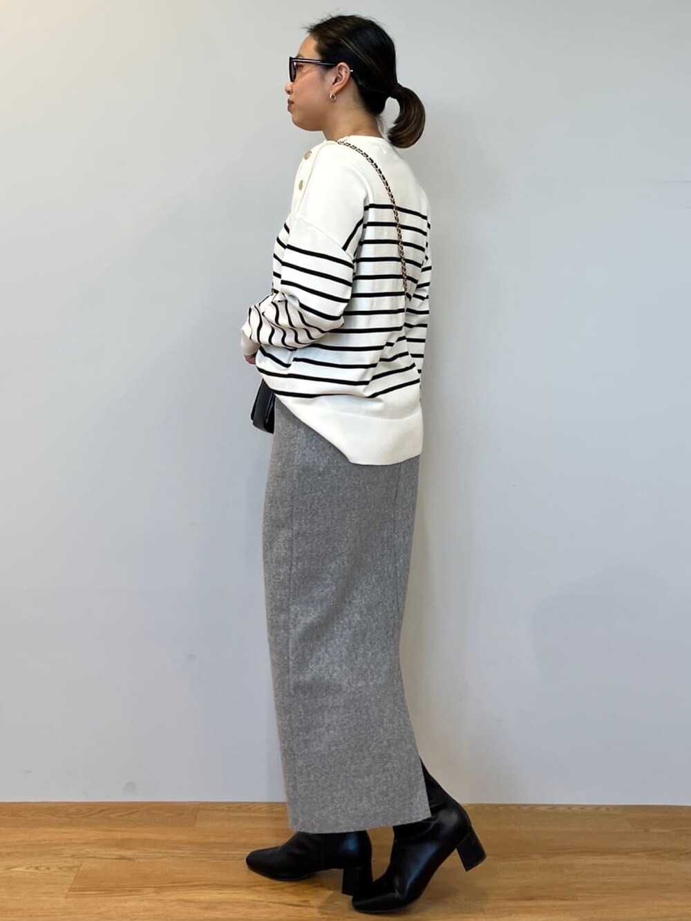 ホワイト系のニット/セーター、グレー系のスカート、ブラック系のショルダーバッグを着用したレディースの冬コーディネートの2枚目の写真