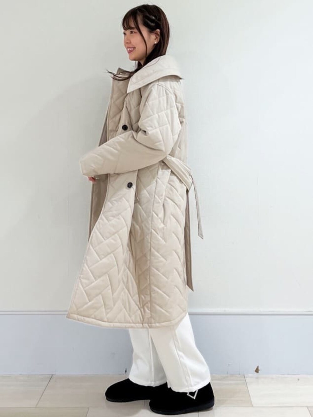 ベージュ系のステンカラーコート、ブルー系のニット/セーター、ホワイト系のその他パンツを着用したレディースの冬コーディネートの2枚目の写真