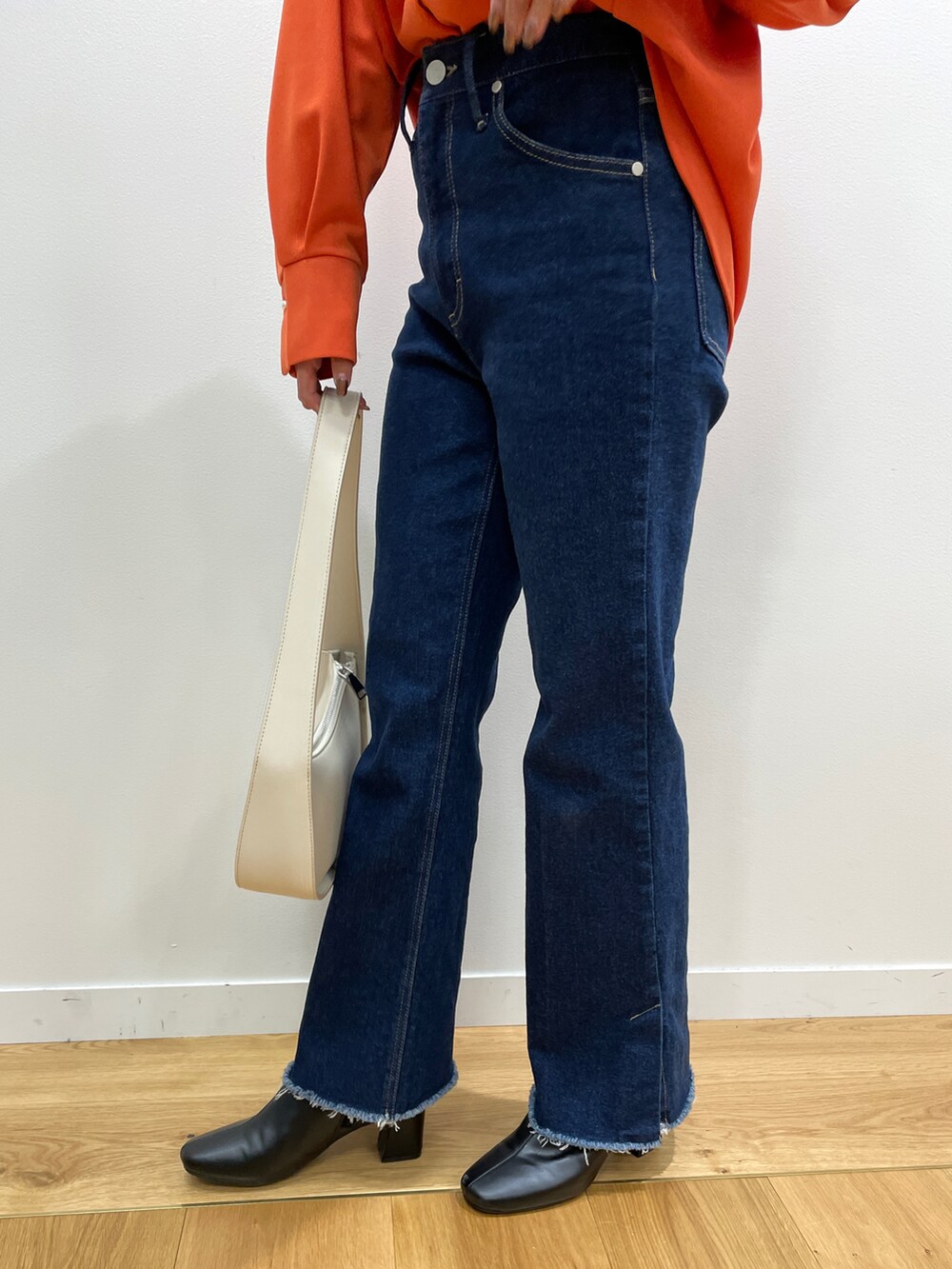 オレンジ系のTシャツ/カットソー、ブルー系のその他パンツ、ブラック系のブーツを着用したレディースの秋コーディネートの5枚目の写真