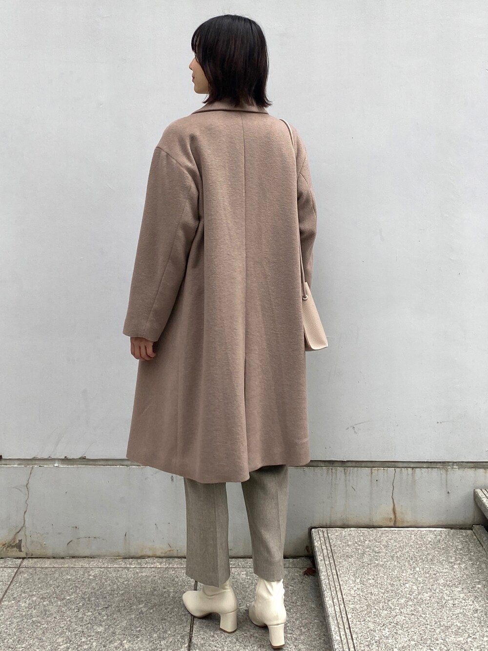 ベージュ系のチェスターコート、ベージュ系のその他パンツ、ホワイト系のブーツを着用したレディースの冬コーディネートの2枚目の写真