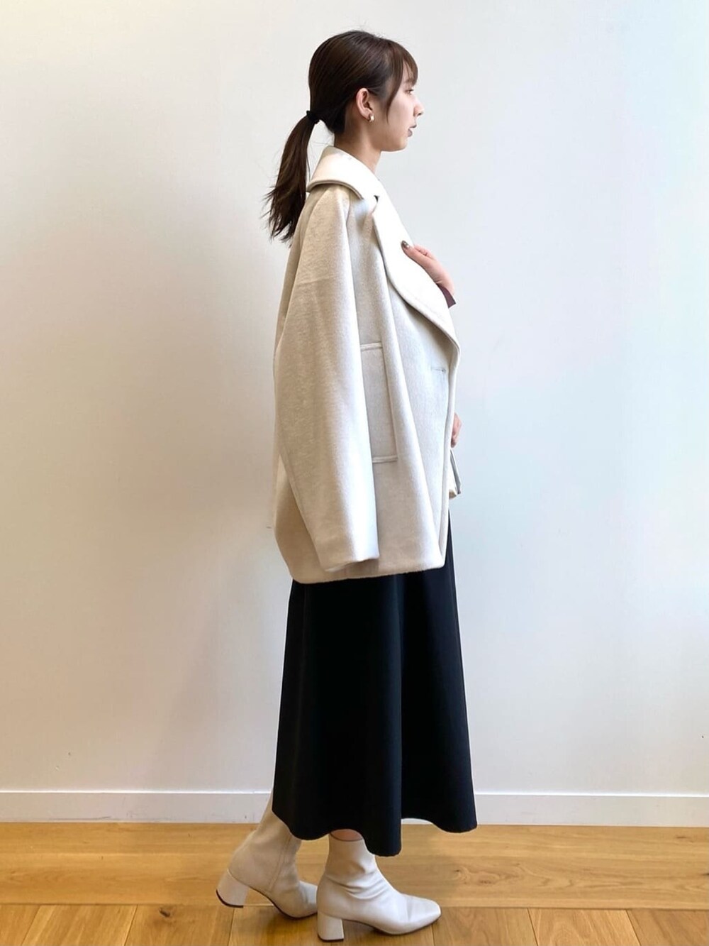 ホワイト系のピーコート、ブラック系のパンプス、ピンク系のワンピースを着用したレディースの冬コーディネートの2枚目の写真