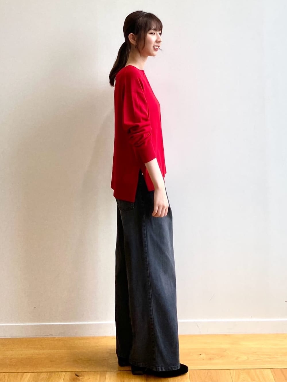 レッド系のニット/セーター、ブラック系のデニムパンツ、ブラック系のパンプスを着用したレディースの秋コーディネートの3枚目の写真