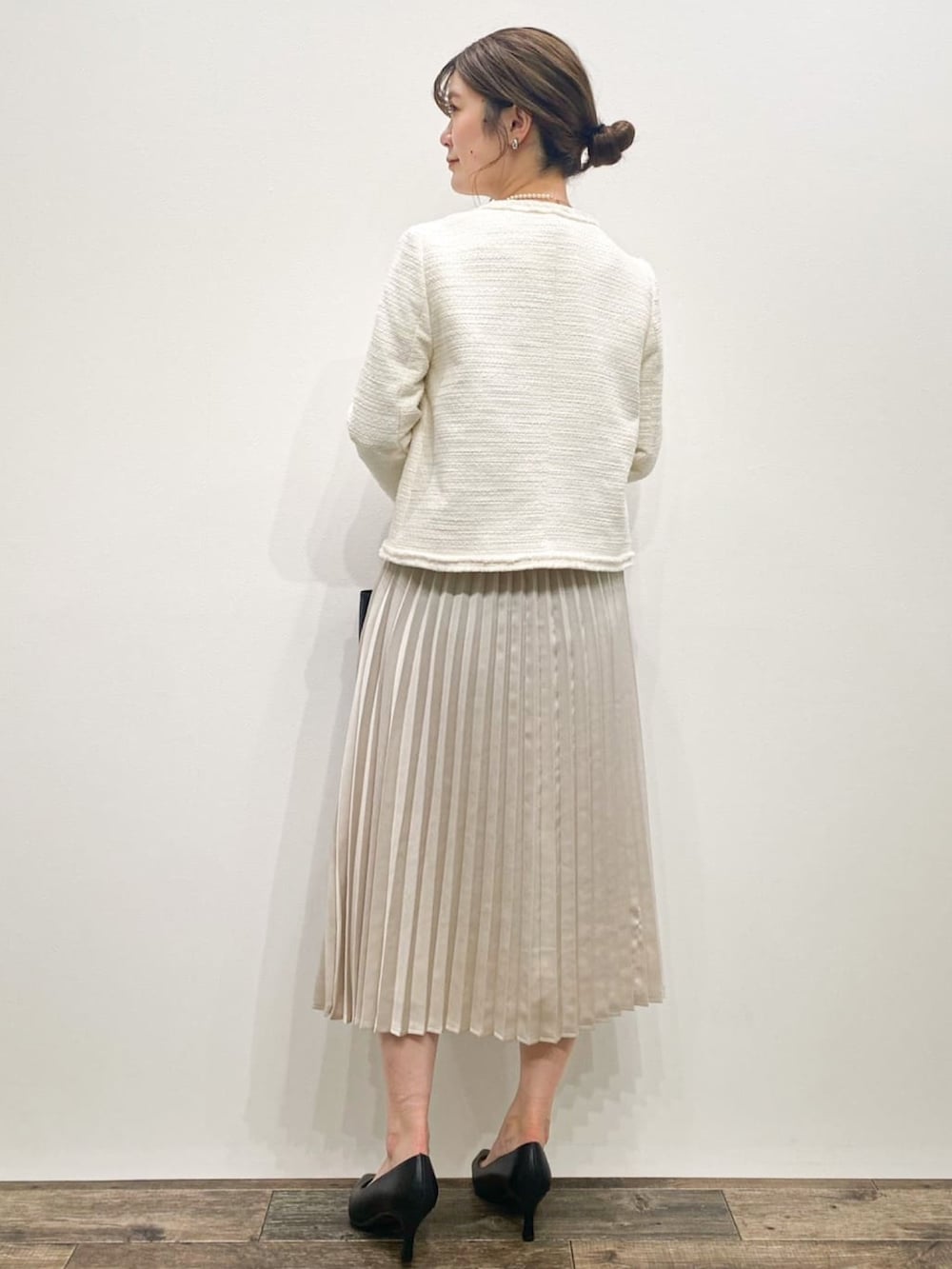 ホワイト系のノーカラージャケット、ベージュ系のワンピース、ブラック系のトートバッグを着用したレディースの冬コーディネートの3枚目の写真