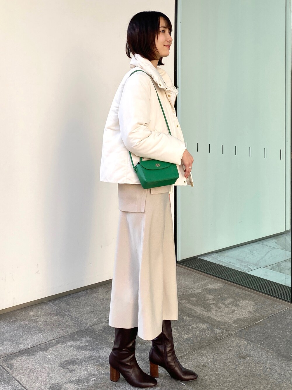 ホワイト系のブルゾン、ベージュ系のニット/セーター、グリーン系のショルダーバッグを着用したレディースの冬コーディネートの2枚目の写真