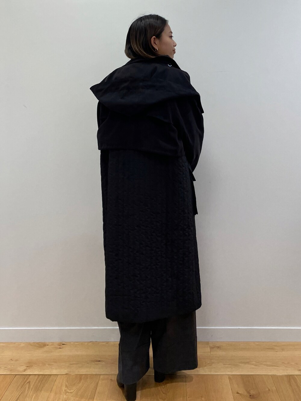 ブラック系のトレンチコート、ピンク系のニット/セーター、ブラック系のブーツを着用したレディースの秋コーディネートの2枚目の写真