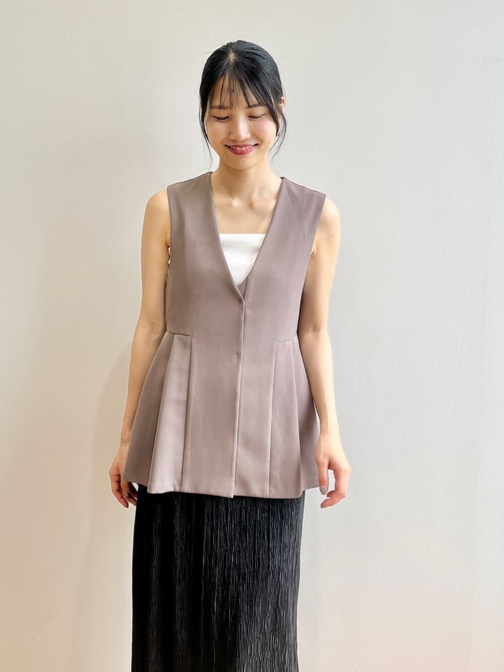 ホワイト系のタンクトップ、ホワイト系のサンダル、ブラウン系のベストを着用したレディースの夏コーディネートの5枚目の写真