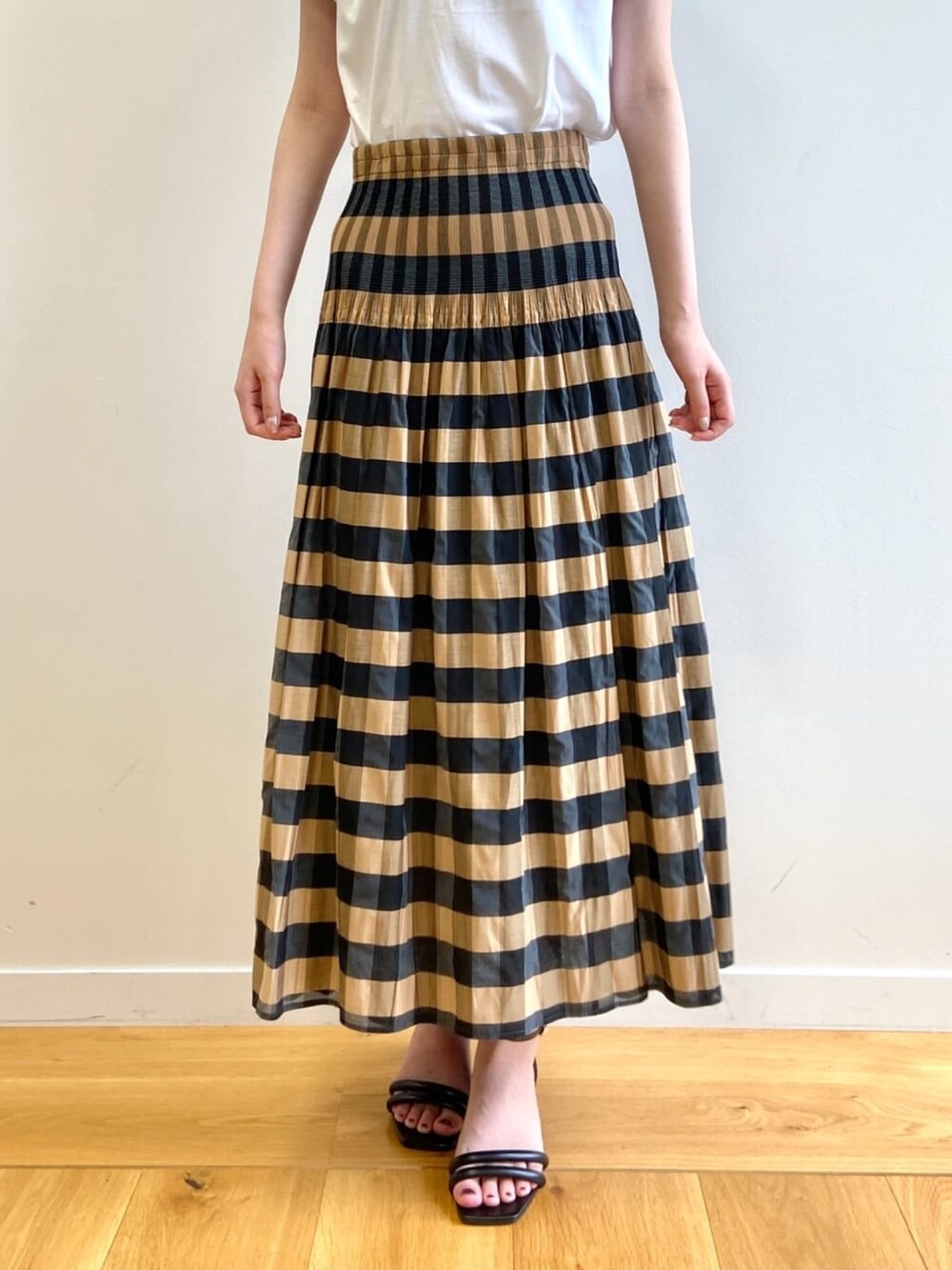 ベージュ系のスカート、ホワイト系のTシャツ/カットソー、ブラック系のサンダルを着用したレディースの夏コーディネートの8枚目の写真