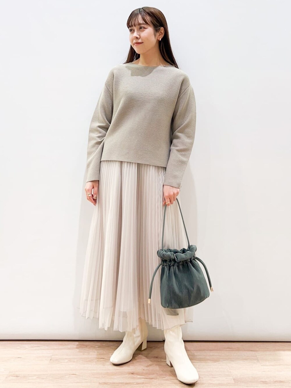 ベージュ系のスカート、ベージュ系のニット/セーター、ホワイト系のブーツを着用したレディースの冬コーディネートの2枚目の写真