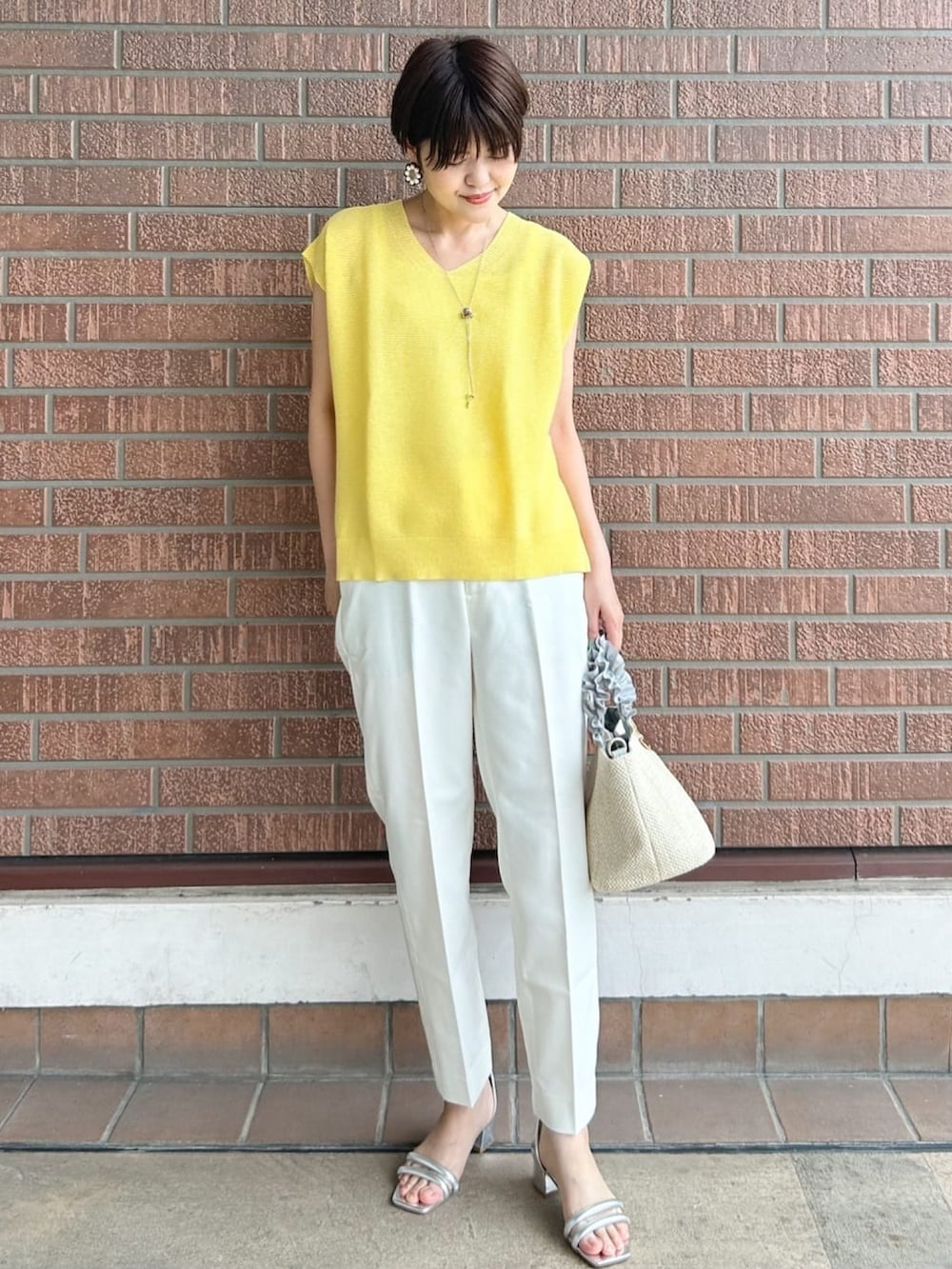 ホワイト系のその他パンツ、グレー系のトートバッグ、シルバー系のサンダルを着用したレディースの春コーディネートの2枚目の写真