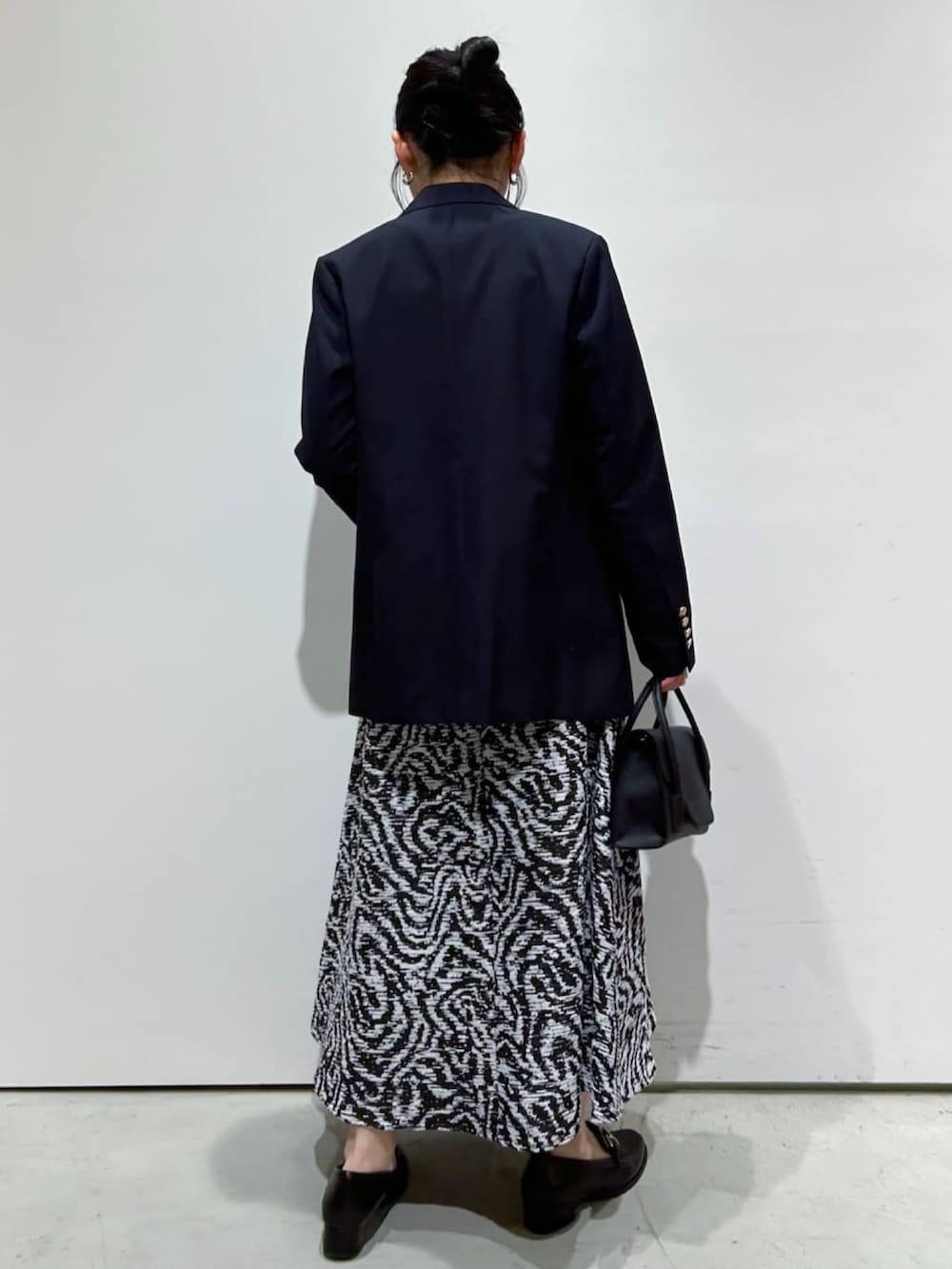 イエロー系のニット/セーター、ブルー系のテーラードジャケット、ブラック系のスカートを着用したレディースの冬コーディネートの2枚目の写真