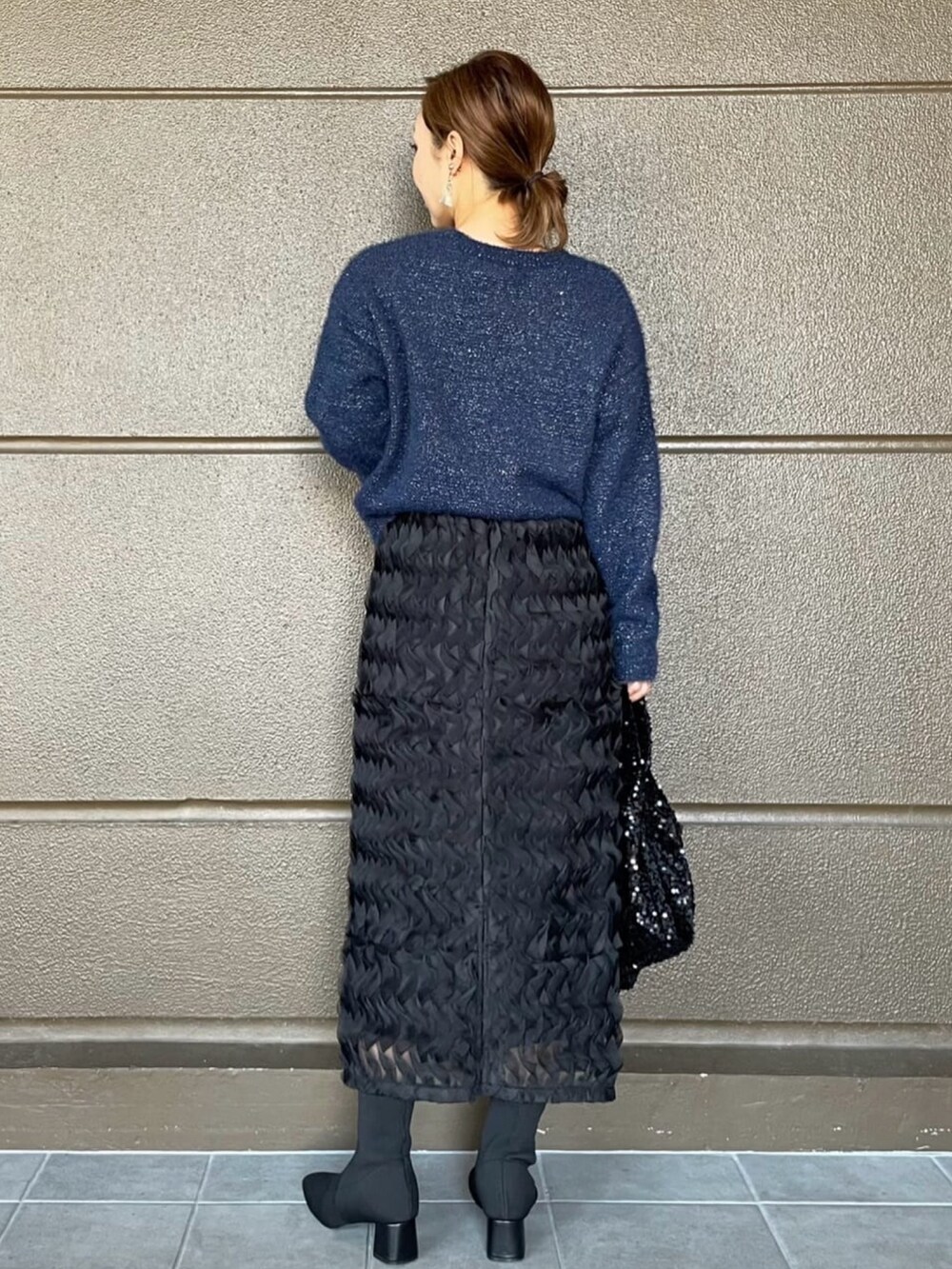 ブラック系のスカート、ブルー系のニット/セーター、ブラック系のブーツを着用したレディースの秋コーディネートの4枚目の写真