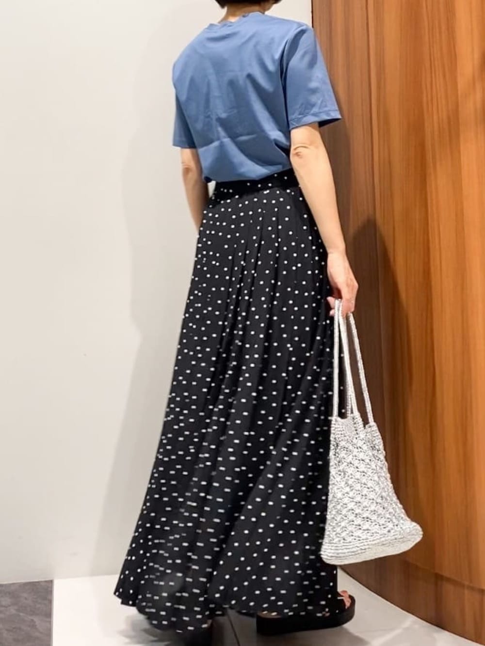 ブラック系のスカート、ブラック系のサンダル、シルバー系のトートバッグを着用したレディースの夏コーディネートの4枚目の写真