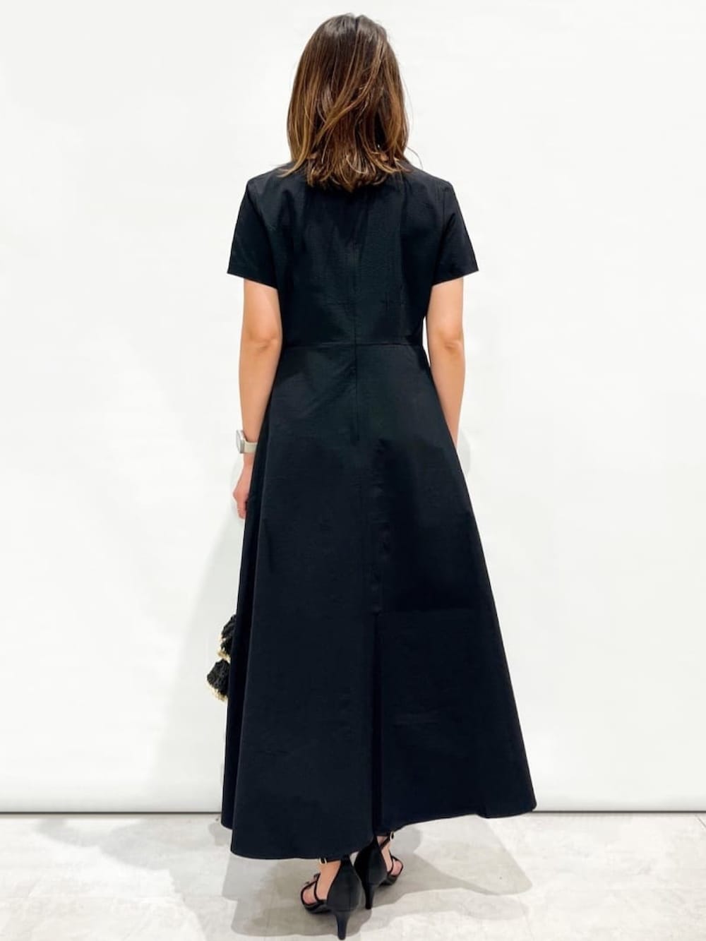 ブラック系のワンピース、ブラック系のトートバッグ、ブラック系のサンダルを着用したレディースの夏コーディネートの3枚目の写真