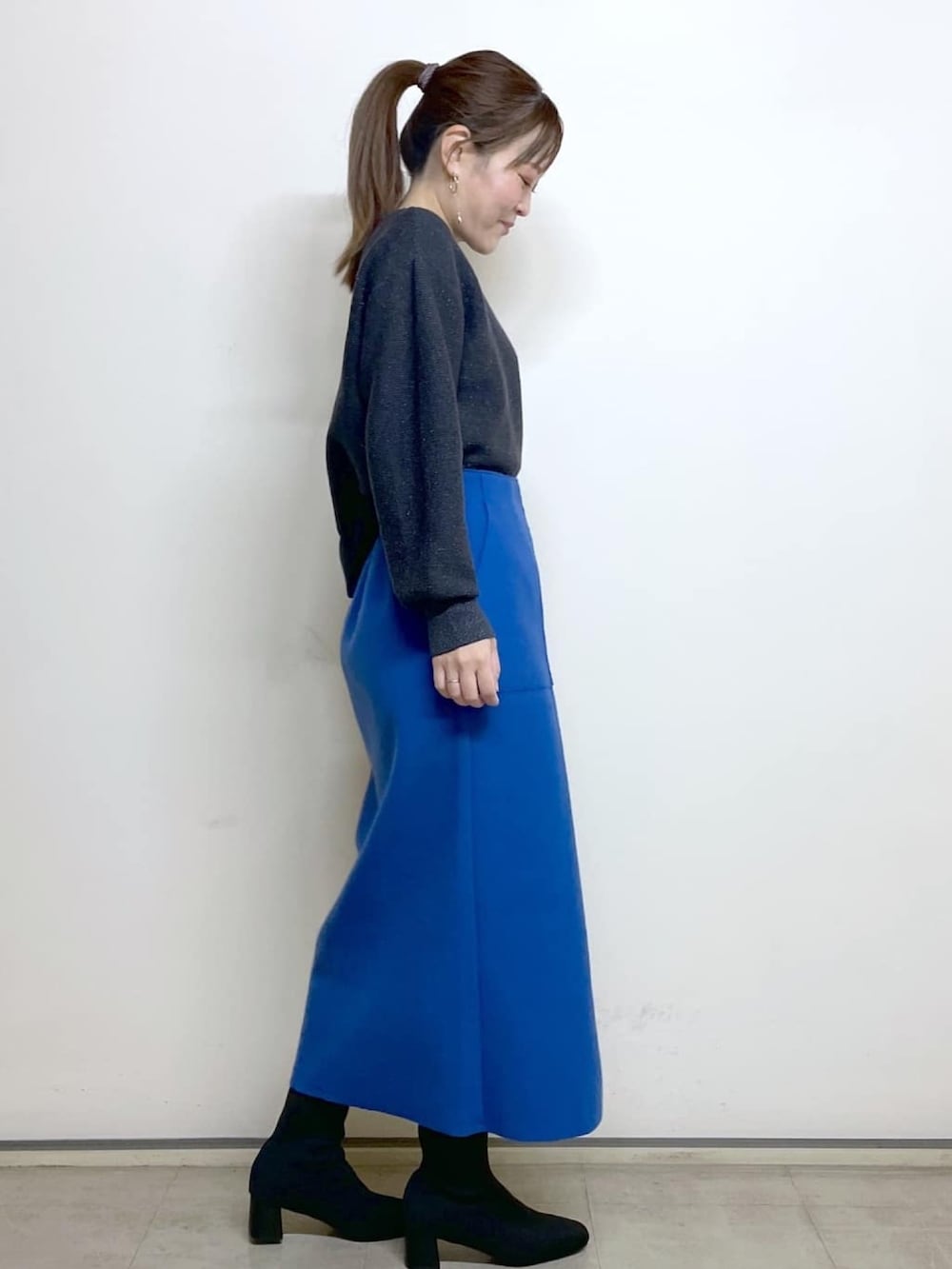 ブラック系のチェスターコート、ブルー系のスカート、ブラック系のブーツを着用したレディースの冬コーディネートの5枚目の写真