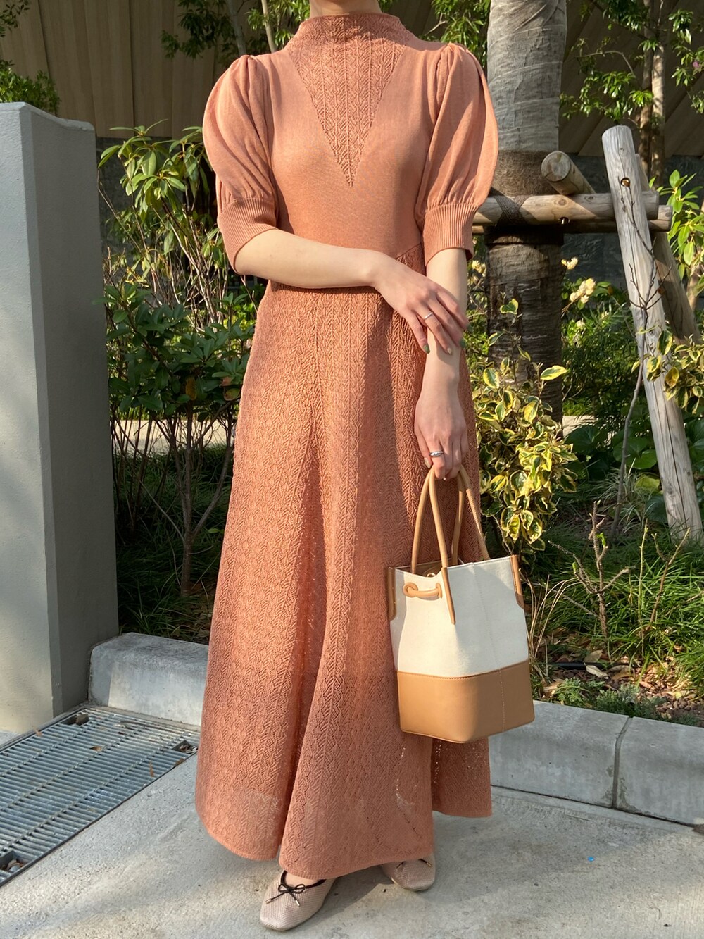 オレンジ系のワンピース、ベージュ系のドレスシューズ、イエロー系のトートバッグを着用したレディースの春コーディネートの3枚目の写真